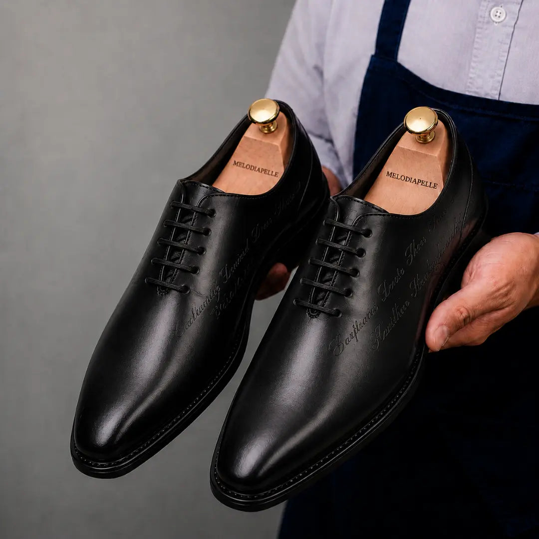 Man holding a pair of Melodiapelle Mordecai Script Wholecut Oxford shoes in black leather, close-up