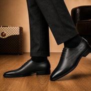 Melodiapelle Mordecai Script Wholecut Oxford in black leather worn with formal trousers, on-feet shot