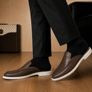 Melodiapelle Moreno Mule in dark brown croc-embossed leather worn with trousers, on-feet shot