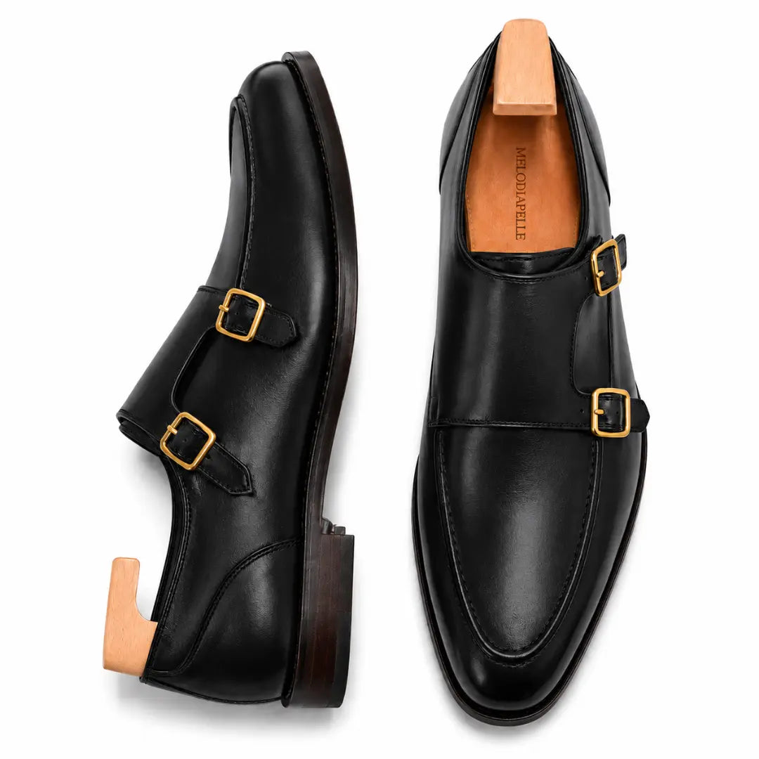 Black leather double monk strap shoe, three-quarter angle showing buckles and heel