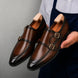 Man holding a pair of Melodiapelle Mortimer Apron Monk Strap shoes in cognac brown leather, close-up