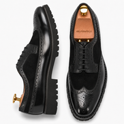 Two-tone nero black leather wingtip Derby, three-quarter angle showing heel and brogue detailing