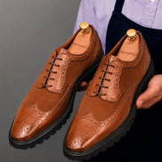 Man holding a pair of Melodiapelle Mosaic Two-Tone Wingtip Derby shoes in tan leather, close-up