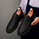Man holding a pair of Melodiapelle Moscow Opera Slip-On shoes in black leather, close-up