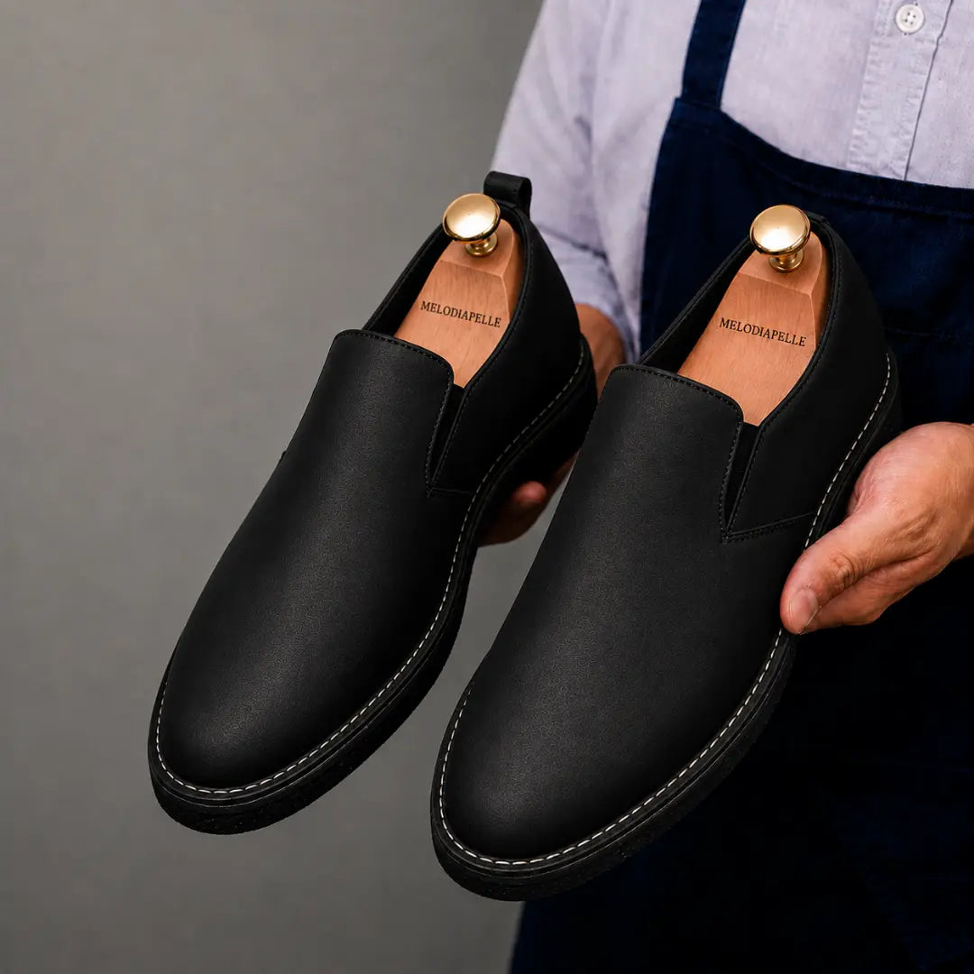 Man holding a pair of Melodiapelle Moscow Opera Slip-On shoes in black leather, close-up