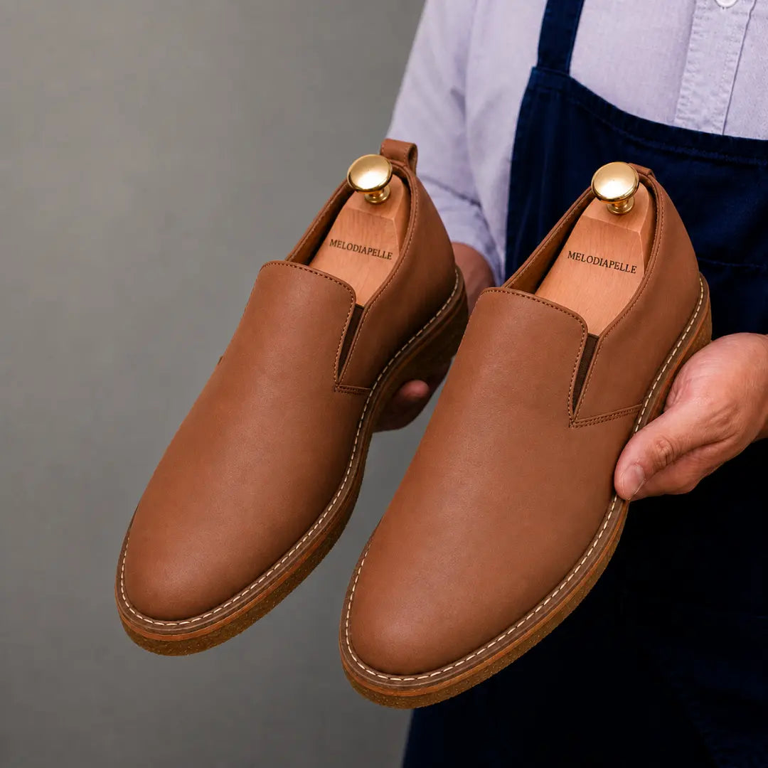 Man holding a pair of Melodiapelle Moscow Opera Slip-On shoes in tan leather, close-up