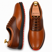 Two-tone tan and dark brown leather golf shoe, three-quarter angle showing heel and stitching detail