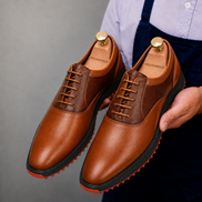 Man holding a pair of Melodiapelle Motif Golf Shoes in tan and dark brown leather, close-up