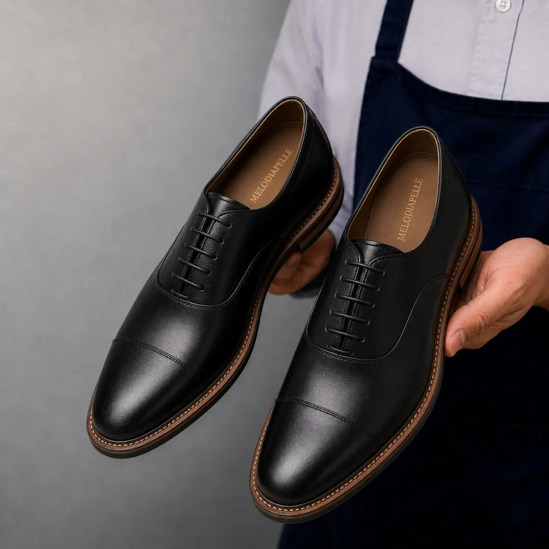 Man holding a pair of Melodiapelle Mount Pleasant Oxford shoes in black leather, close-up