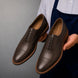 Man holding a pair of Melodiapelle Mount Pleasant Oxford shoes in dark brown leather, close-up