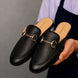 Man holding a pair of Melodiapelle Mustang Mules in black leather, close-up